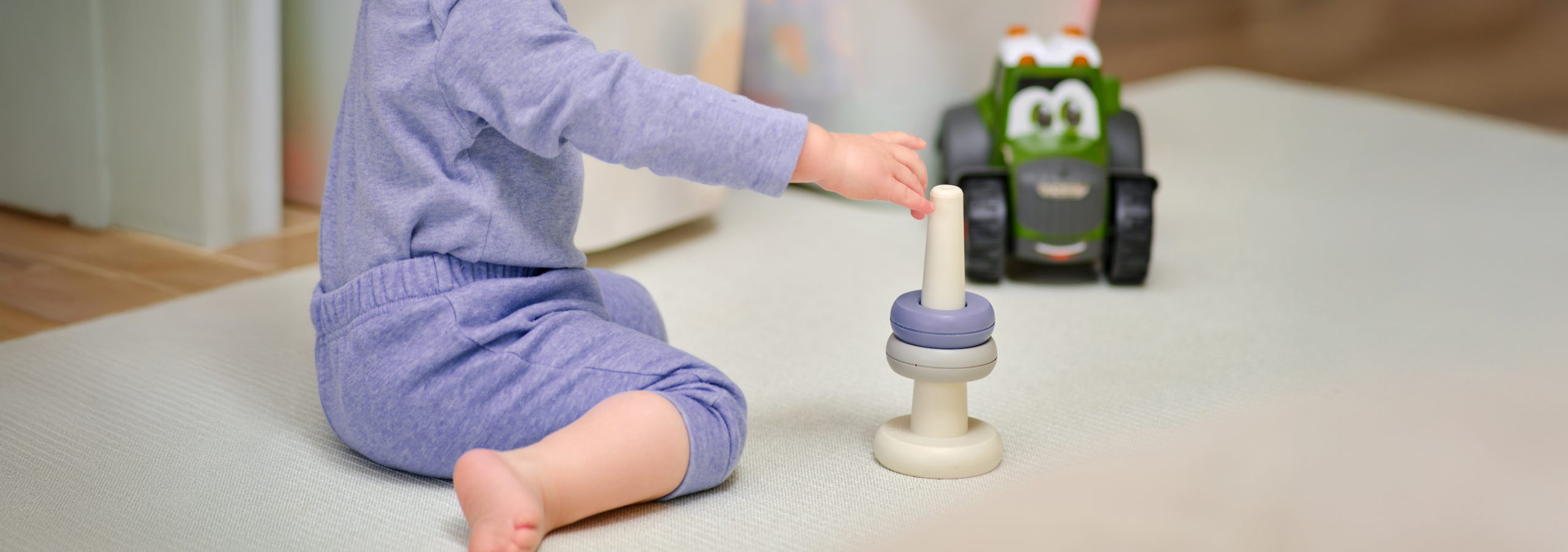 Toddler baby boy playing pyramid on the floor in the home room. Child playing with toys in the children's room. Kid aged one year and three months
